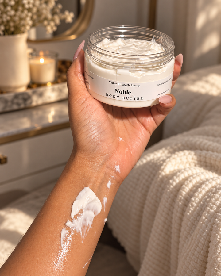 Hand holding Noble body butter beside a cream swatch